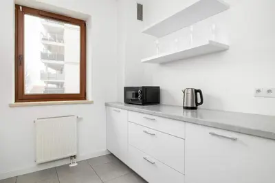 a kitchen with white cabinets and a microwave at Bright One-Bedroom Apartment Functional Interiors Remote Working by Noclegi Renters in Kraków