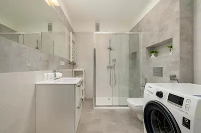 a bathroom with a shower and a washing machine at Bright One-Bedroom Apartment Functional Interiors Remote Working by Noclegi Renters in Kraków