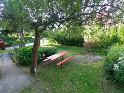 a red bench sitting under a tree in a park at Przytulny pokój z łazienką Cosy Room with Bathroom in Rabka
