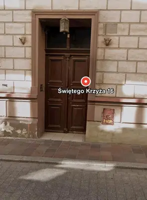 a brown door on a building with a sign on it at Saint Cross Apartment in Kraków