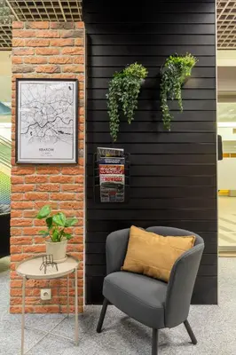 a chair and a table with plants on a wall at Vistula Lounge - Night Access - Kraków Główny in Kraków