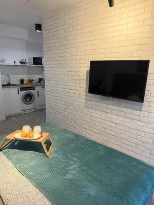 a living room with a tv on a brick wall at Golden Honey Apartment- Studio Cracow Old Town in Kraków