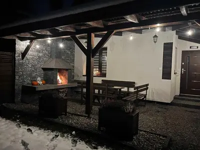 a patio with a fireplace and a table and a bench at Domek u Gosi
