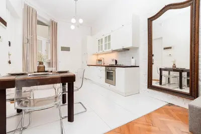 a white kitchen with a mirror and a table at Vintage Soul Ariańska in Kraków