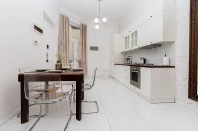 a white kitchen with a table and a counter at Vintage Soul Ariańska in Kraków