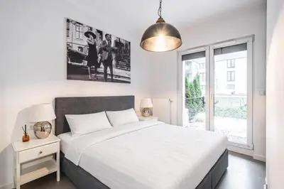 a white bedroom with a large bed and a window at RentPlanet - Apartament Rakowicka in Kraków