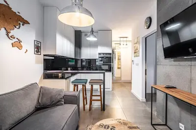 a living room with a couch and a kitchen at RentPlanet - Apartament Rakowicka in Kraków
