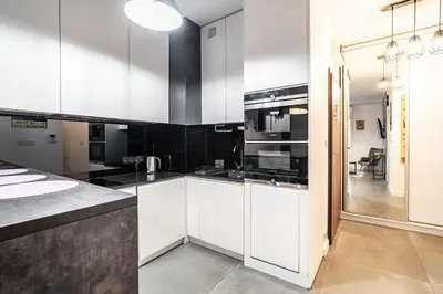 a kitchen with white cabinets and black counters at RentPlanet - Apartament Rakowicka in Kraków