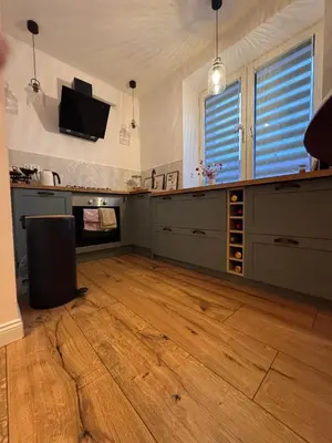 a large kitchen with wooden floors and a flat screen tv at The Nest, Apartament in Oświęcim