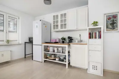a kitchen with white cabinets and a white refrigerator at Bright Apartment in Kraków Perfect for Remote Work by Noclegi Renters in Kraków