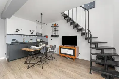 a living room with a table and a tv and a staircase at Parkside Design Loft in Kraków