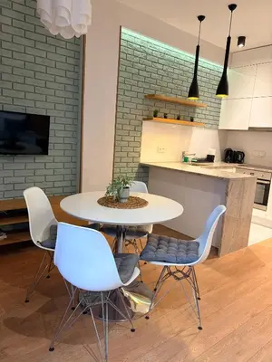 a dining room with a table and chairs and a kitchen at Apartament Rakowicka in Kraków