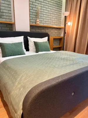 a large bed with two green pillows on it at Apartament Rakowicka in Kraków
