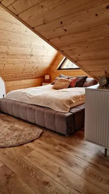 a large bed in a room with wooden ceilings at Domek Jaworówka in Zawoja