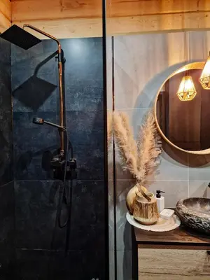 a shower with a glass door next to a table at Domek Jaworówka in Zawoja