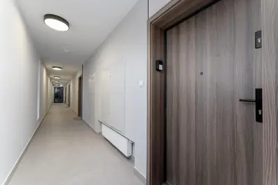 a hallway with a wooden door and a hallway sidx sidx at Prokocim Superior Apartment by BookingHost in Kraków