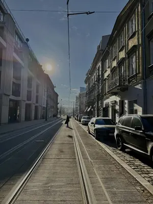 a person walking down a city street with parked cars at Stylish 1BR for 4 in Old Town - Main Square in Kraków