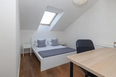 a bedroom with a bed and a table and a window at 4 Bedroom apartment with a balcony - Trynitarska 6 in Kraków