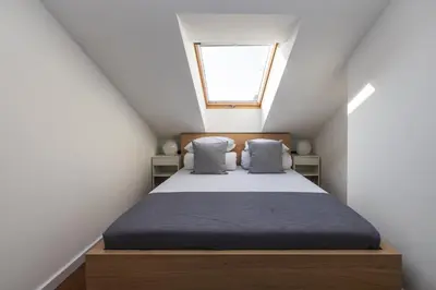 a attic bedroom with a bed with a window at 4 Bedroom apartment with a balcony - Trynitarska 6 in Kraków