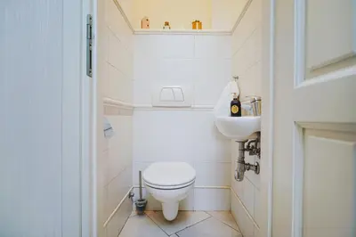 a white bathroom with a toilet and a sink at Downtown Cozy Corner in Kraków