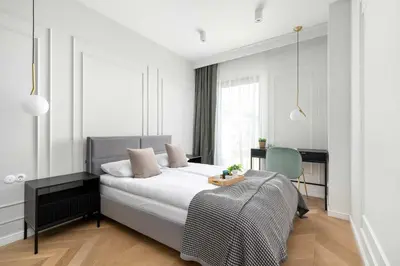 a white bedroom with a bed and a desk at Atmospheric Apartment with Ideal Location in Cracow by Noclegi Renters in Kraków
