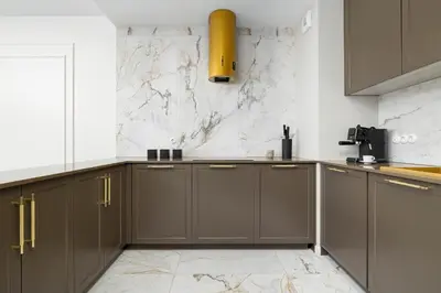 a kitchen with brown cabinets and a marble wall at Atmospheric Apartment with Ideal Location in Cracow by Noclegi Renters in Kraków