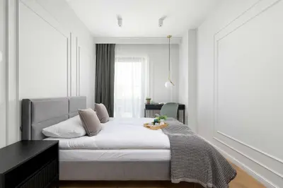 a bedroom with a white bed with a black desk at Atmospheric Apartment with Ideal Location in Cracow by Noclegi Renters in Kraków