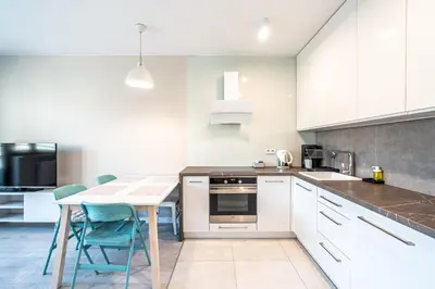 a kitchen with white cabinets and a table and chairs at RentPlanet - Apartament Rydlówka in Kraków