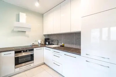 a white kitchen with white cabinets and a sink at RentPlanet - Apartament Rydlówka in Kraków