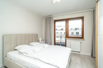 a white bedroom with a large bed and a window at RentPlanet - Apartament Rydlówka in Kraków