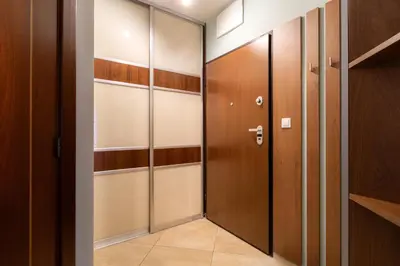 a walk in closet with wooden doors and shelves at Malila Premium Apartments Cracow Pułaskiego 14 in Kraków