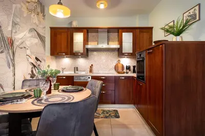 a kitchen with a wooden table with chairs and a tableasteryasteryasteryasteryastery at Malila Premium Apartments Cracow Pułaskiego 14 in Kraków