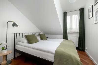 a bedroom with a bed with white sheets and green pillows at Family Two-Level Apartment with Air Conditioning by Noclegi Renters in Kraków