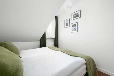 a white bedroom with a bed and two pictures on the wall at Family Two-Level Apartment with Air Conditioning by Noclegi Renters in Kraków