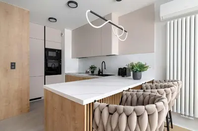 a kitchen with a white counter and bar stools at Stylowy Apartament z Parkingiem & Balkonem, Blisko Wisły by Noclegi Renters in Kraków