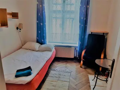 a small room with a bed and a chair and a window at Let's go back to the memories in Kraków
