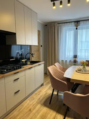 a kitchen with white cabinets and a dining table at Apartament Paoli 2 in Zator