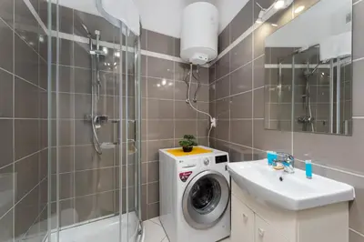a bathroom with a washing machine and a sink at Cracow Downtown Comfort Studio by BookingHost in Kraków