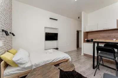 a bedroom with a bed and a table and a kitchen at Cracow Downtown Comfort Studio by BookingHost in Kraków
