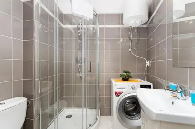 a bathroom with a washing machine and a sink at Cracow Downtown Comfort Studio by BookingHost in Kraków