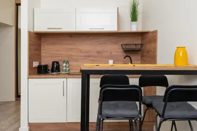 a kitchen with white cabinets and a table with chairs at Cracow Downtown Comfort Studio by BookingHost in Kraków