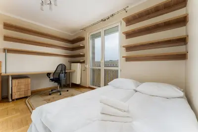 a bedroom with a bed and a desk and a window at Nowa Huta Standard Apartment by BookingHost in Kraków