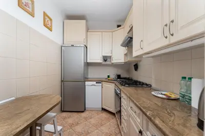 a kitchen with white cabinets and a stainless steel refrigerator at Nowa Huta Standard Apartment by BookingHost in Kraków