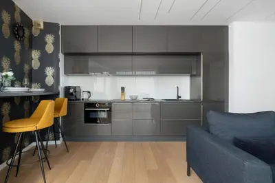 a kitchen with gray cabinets and yellow chairs in a living room at Tasteful Apartment in Cracow with Parking & Balcony by Nolcegi Renters in Kraków