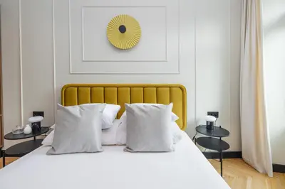 a white bed with white pillows and a yellow headboard at 3 bedroom - Grodzka Street - Old Town in Kraków