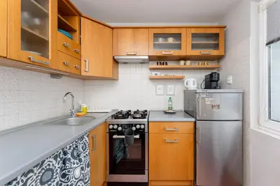 a kitchen with wooden cabinets and a stainless steel refrigerator at Nowa Huta Charming Details Apartment by BookingHost in Kraków