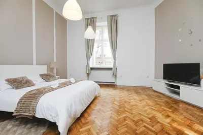 a white bedroom with a large bed and a flat screen tv at Old Town Sarego Apartment in Kraków