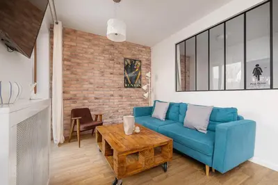a living room with a blue couch and a brick wall at 3-Bedroom apartment in Historic Kazimierz in Kraków