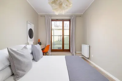 a white bedroom with a bed and a window at 3-Bedroom apartment in Historic Kazimierz in Kraków