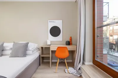 a bedroom with a desk and a bed and a orange chair at 3-Bedroom apartment in Historic Kazimierz in Kraków